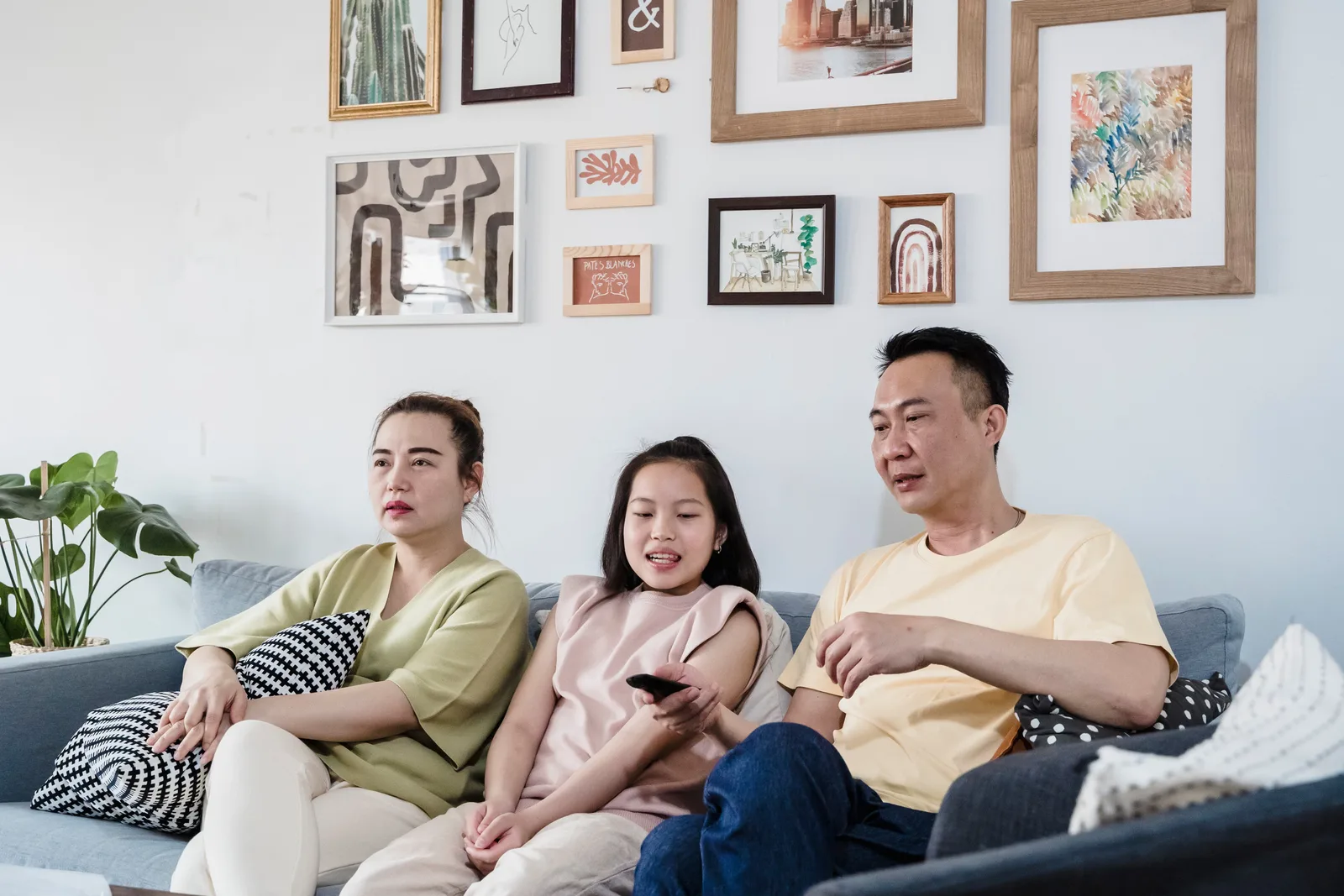 A family of three relaxing together on the sofa in their cozy living room, enjoying a TV show.